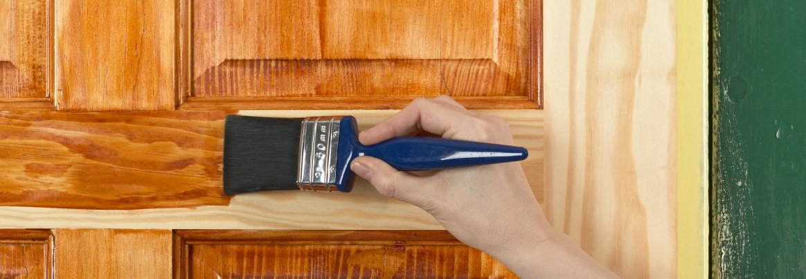 Holztür wird mit Pinsel lasiert.